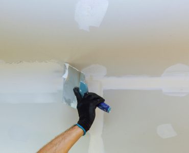 Worker puttied wall using a paint spatula hand worker repairs gypsum plasterboard